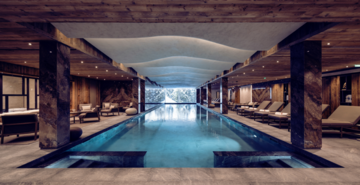 La piscine d'une résidence de tourisme haut de gamme avec vue sur les montagnes enneigées.