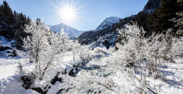 Photo d'un beau paysage au niveau du lac de Tueda avec le soleil qui scintille dans la neige fraîche.