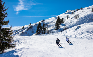 Un couple skie à Méribel sous un magnifique ciel bleu.
