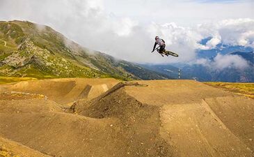 Rider effectuant un saut sur un module de la piste DH1 du Bike Park de Méribel, en haute montagne
