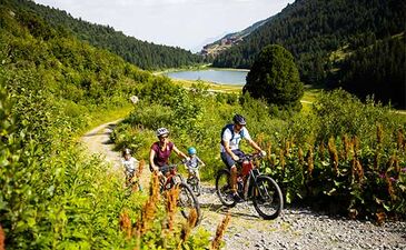 Balade en famille à VTT sur un chemin forestier à Méribel, près du lac de Tuéda